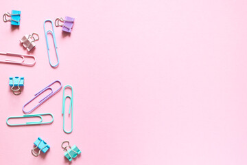 Multi-colored paper clips laid out on a delicate pink background. Layout and flat lay with place for text. Concept back to school.