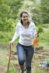 Woman holding carrots and spading fork