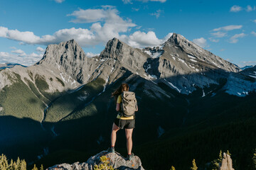 Hiker woman overlooking beautiful mountain scenery of the iconic Three Sisters above Canmore from...