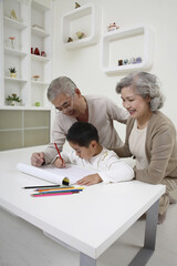 Obraz premium Boy drawing with coloured pencil, senior couple watching