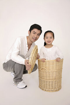 Girl Hiding Inside Laundry Basket, Man Squatting Beside Her