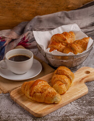 freshly baked croissants with black coffee on grey table for breakfast