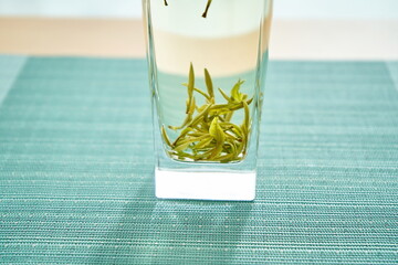 A clear glass with Mao Feng tea in it.