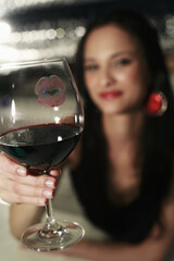 Woman showing glass with lipstick kiss on it