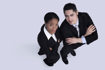 Businessman and businesswoman looking up with arms folded