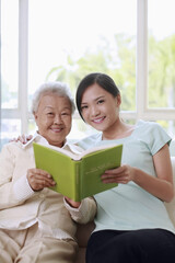 Senior woman and woman reading book together