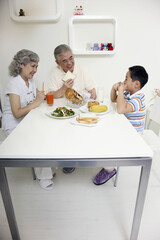 Boy having breakfast with senior man and senior woman