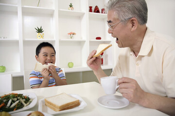 Obraz na płótnie Canvas Senior man and boy eating bread