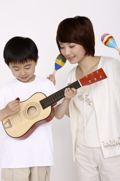 Boy Playing Guitar While Woman Shaking Maracas