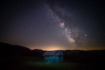 Small abandoned barn farm house shot in the night against a starry sky with milky way galactic core seen above - Powered by Adobe