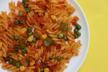 Red fusillli pasta with vegetables, corn, peas, red sauce