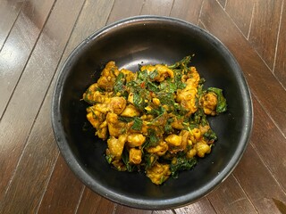 Stir fried chicken with basil in black plate on wood table