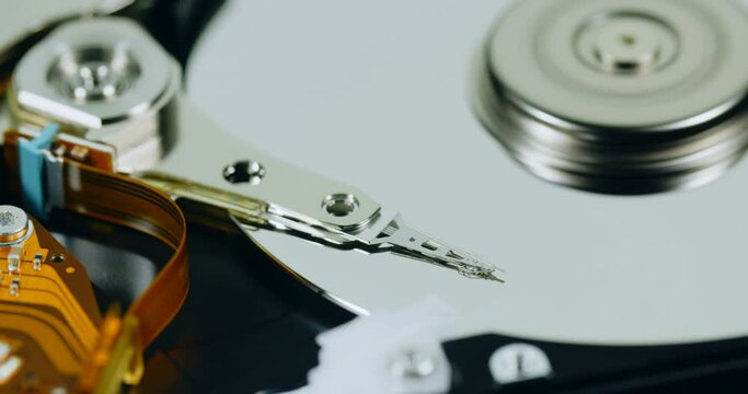 Panning closeup shot of a hard disk reading head moving over a spinning platter.