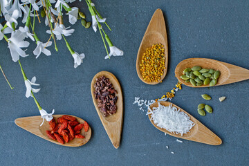 Various legumes and different kinds of nuts in spoons. Walnuts kernels ,hazelnuts, almond ,brown pinto ,soy beans ,flax seeds ,chia ,red kidney beans and pecan set up on white gray background