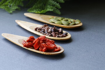 Various legumes and different kinds of nuts in spoons. Walnuts kernels ,hazelnuts, almond ,brown pinto ,soy beans ,flax seeds ,chia ,red kidney beans and pecan set up on white gray background