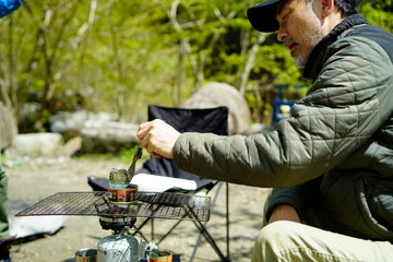 キャンプで缶を温める男性