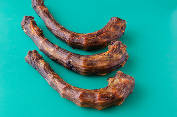 Three dried turkey necks on a turquoise background.