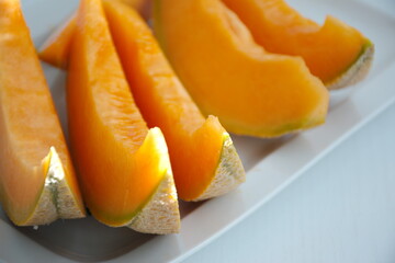 High angle view of orange melon sliced on the plate against a white background