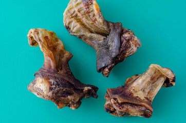 Three Dried beef ears with a turquoise background.