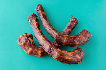 Three Dried turkey neck on a turquoise background.