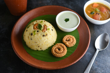 Ven Pongal with Sambar, coconut Chutney popular Indian breakfast food Tamil Nadu festival Pongal made with Rava or semolina in banana leaf plate on white black background top view, South India. 