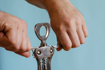 Adult man holds in his hands the metal handle of a corkscrew.