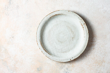 Empty ceramic plate on a light background, top view. Copy space.