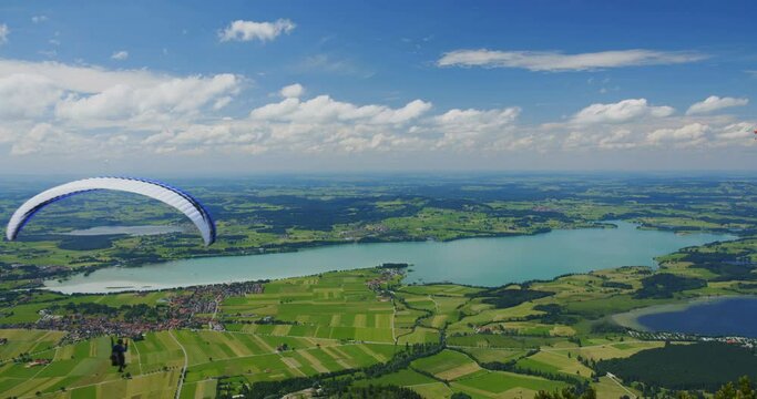 Paraglider flies above lake Forggensee in Bavaria, Germany on a sunny summer day.