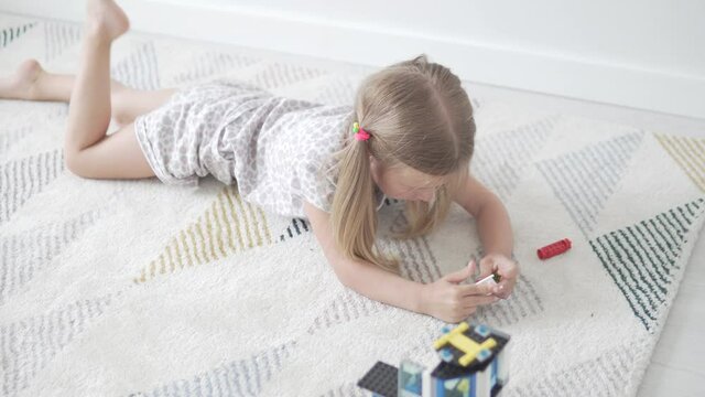 A little stylish girl plays in the designer of the house. A game for the development of fine motor skills in children.