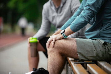 Fit young men taking rest from running. Two friends training outdoors.	