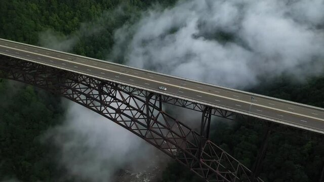 Cinematic Aerial View of Cars Moving on Bridge Above Deep Canyon and Fog of New River Gorge, West Virginia USA