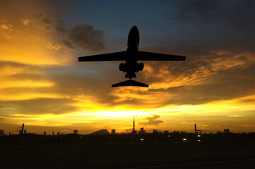 Silhouette airplane flying above big city in sun set time.  Airline business.