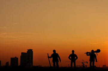 Fototapeta na wymiar Cityscape building and workers team silhouette in twilight time, foreman and team standing with building.