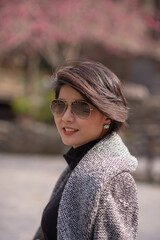 attrative girl face camera under pink cherry blossom sakura tree in the park