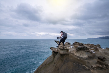 Obraz premium Young camera Man walking to the pit near rock beach