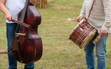 Rural band playing outdoors. Musicians with contrabass and drums performing on the grass outside