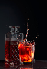 Pieces of ice fall into a frosted glass with whiskey.