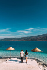 Couple on the beach rear view. Honeymoon lovers. Man and woman on the island. Couple in love on vacation. Sea tour. Honeymoon trip. Couple in love at the blue lagoon. Copy space.  Vertical photo