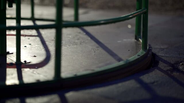 Wet carousel spinning at empty children's playground in city park on an autumn night.