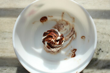 Melted and decorated white Ice Cream with chocolate flavour on top of it. close and cropped display.