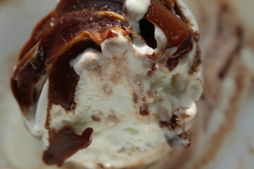 Melted and decorated white Ice Cream with chocolate flavour on top of it. close and cropped display.