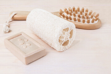 Fototapeta na wymiar Eco-friendly bathroom accessories. Natural soap, loofah washcloth, and wooden massage brush for body. Body care at home. Zero waste concept. Copy space. Selective focus.