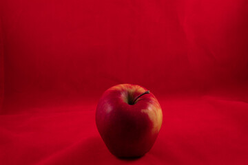 one delicious shiny apple on a red studio background