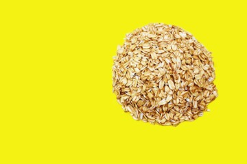 Oatmeal flakes circle isolated on a yellow background, with place for an inscription. Bunting circle symbol. Healthy eating A pile of oatmeal shaped shot from above.