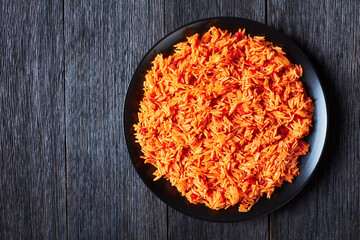 Tomato onion rice on a black plate