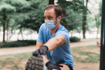 Sportsman with medical mask and gloves, smartphone and earbuds working out, jogging in urban surroundings.