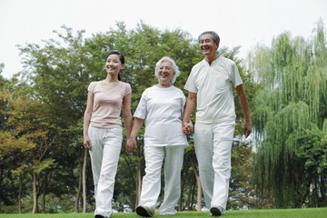 Fototapeta na wymiar Woman together with senior couple holding hands while walking in the park