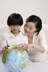 Woman pointing at globe, boy watching