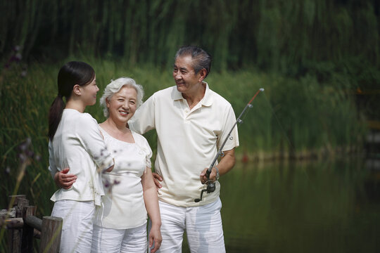 Senior Man Talking To Senior Woman And Woman While Fishing On A Dock