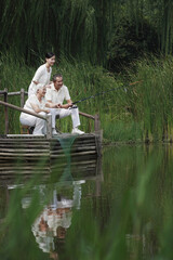 Senior couple sitting on a dock fishing, woman watching